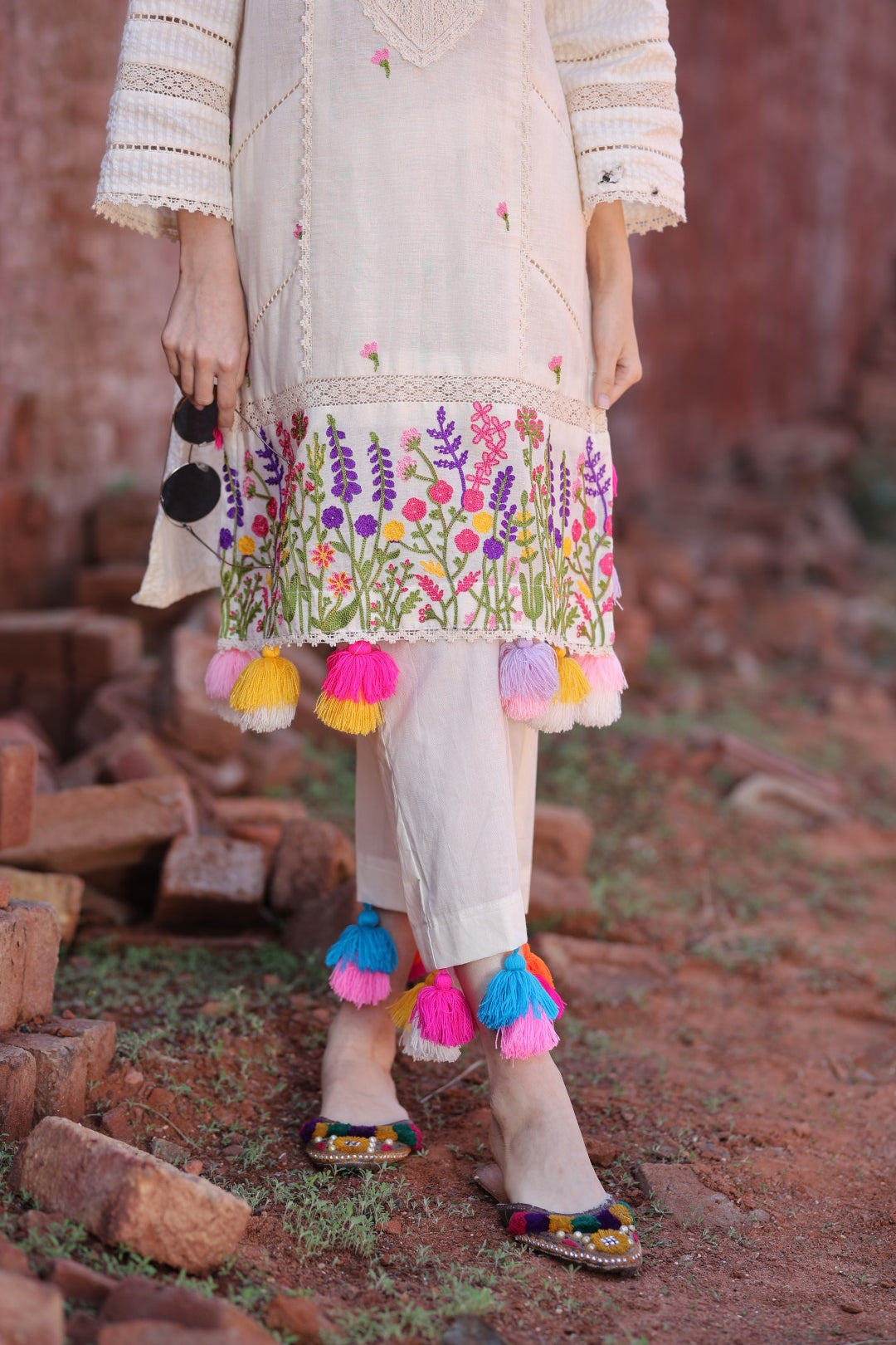 Close-up of hemline embroidery, vibrant tassels, and matching juttis.