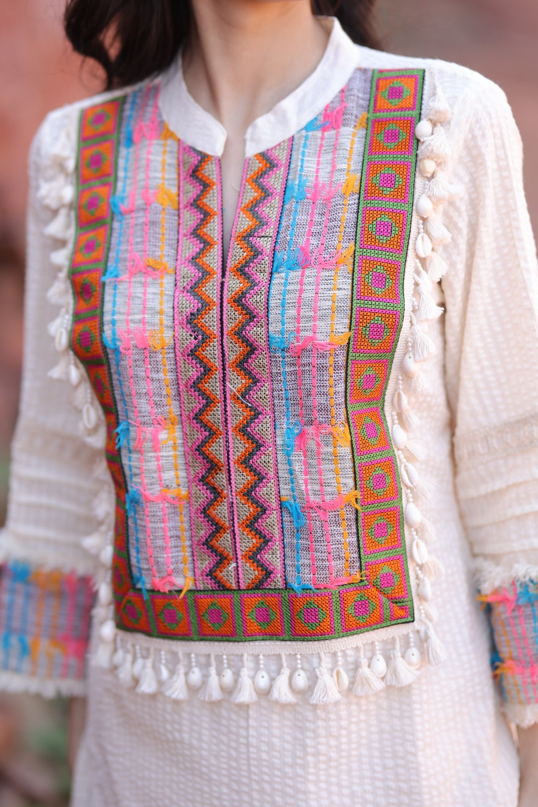 Close-up of patch embroidery and sleeve cuffs with handmade tassels.