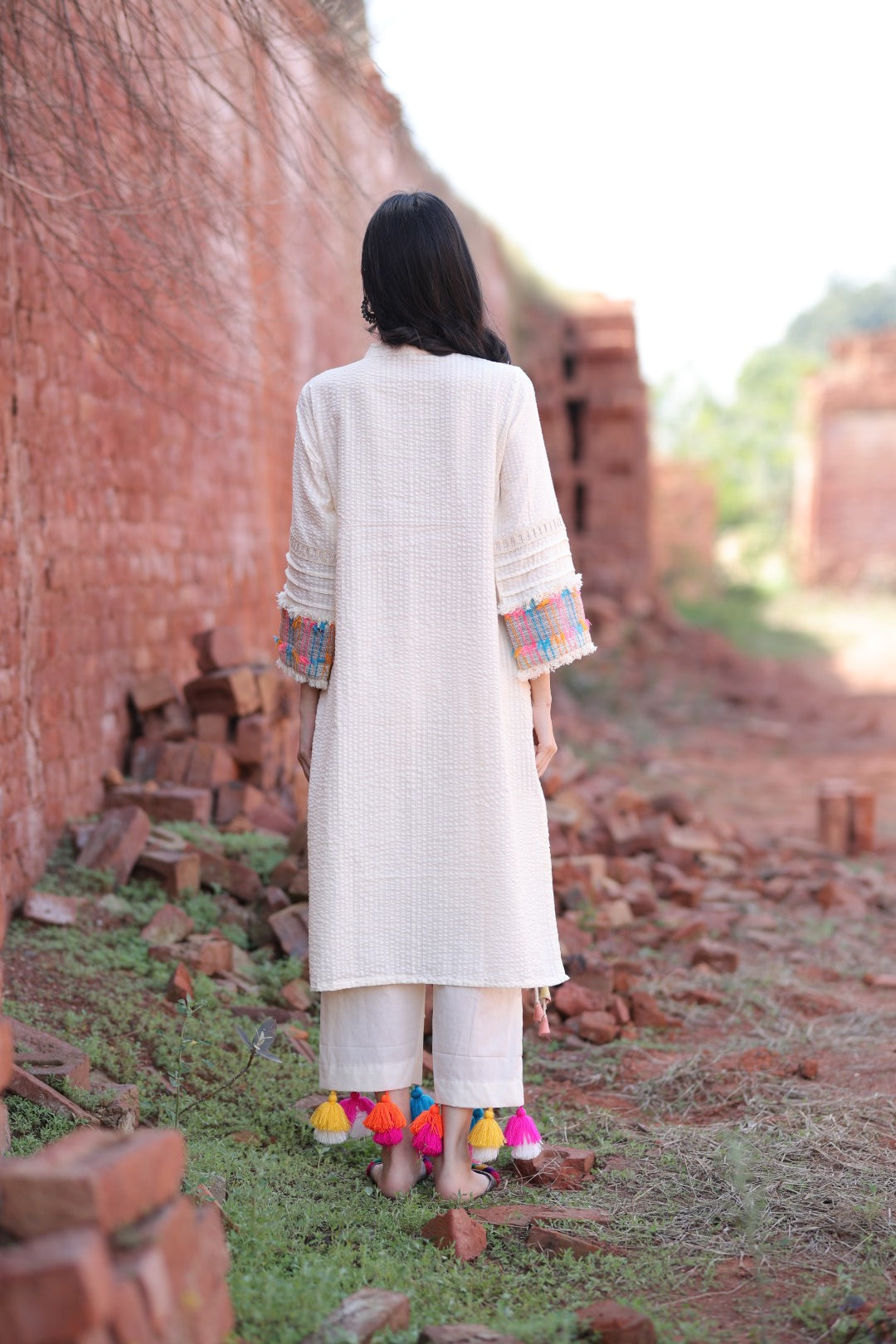Back silhouette of ivory kurta set showing texture and pant tassels