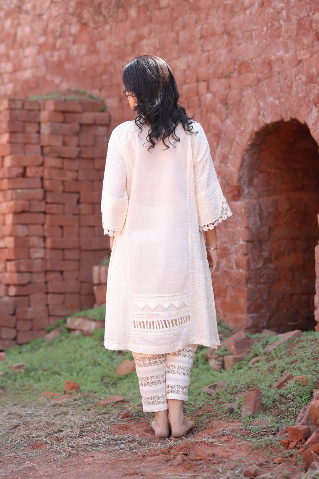 Back view of ivory kurta set with detailed hem and natural texture
