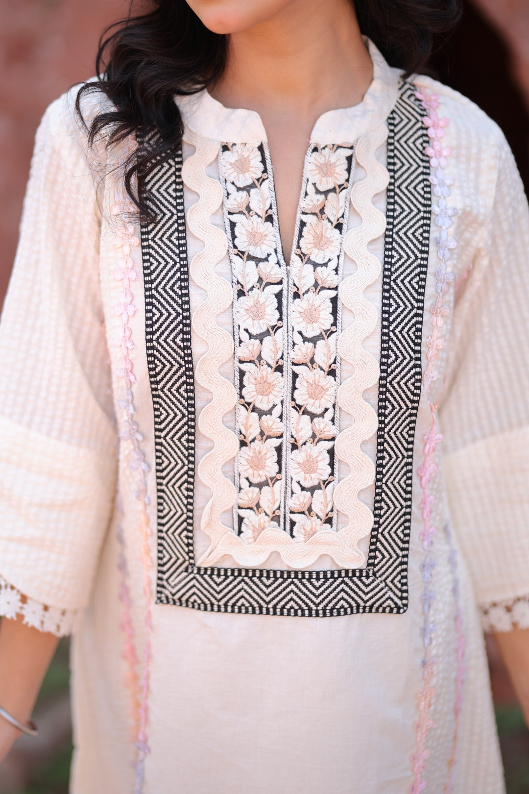 Close-up of geometric embroidery and pastel tassels on yoke