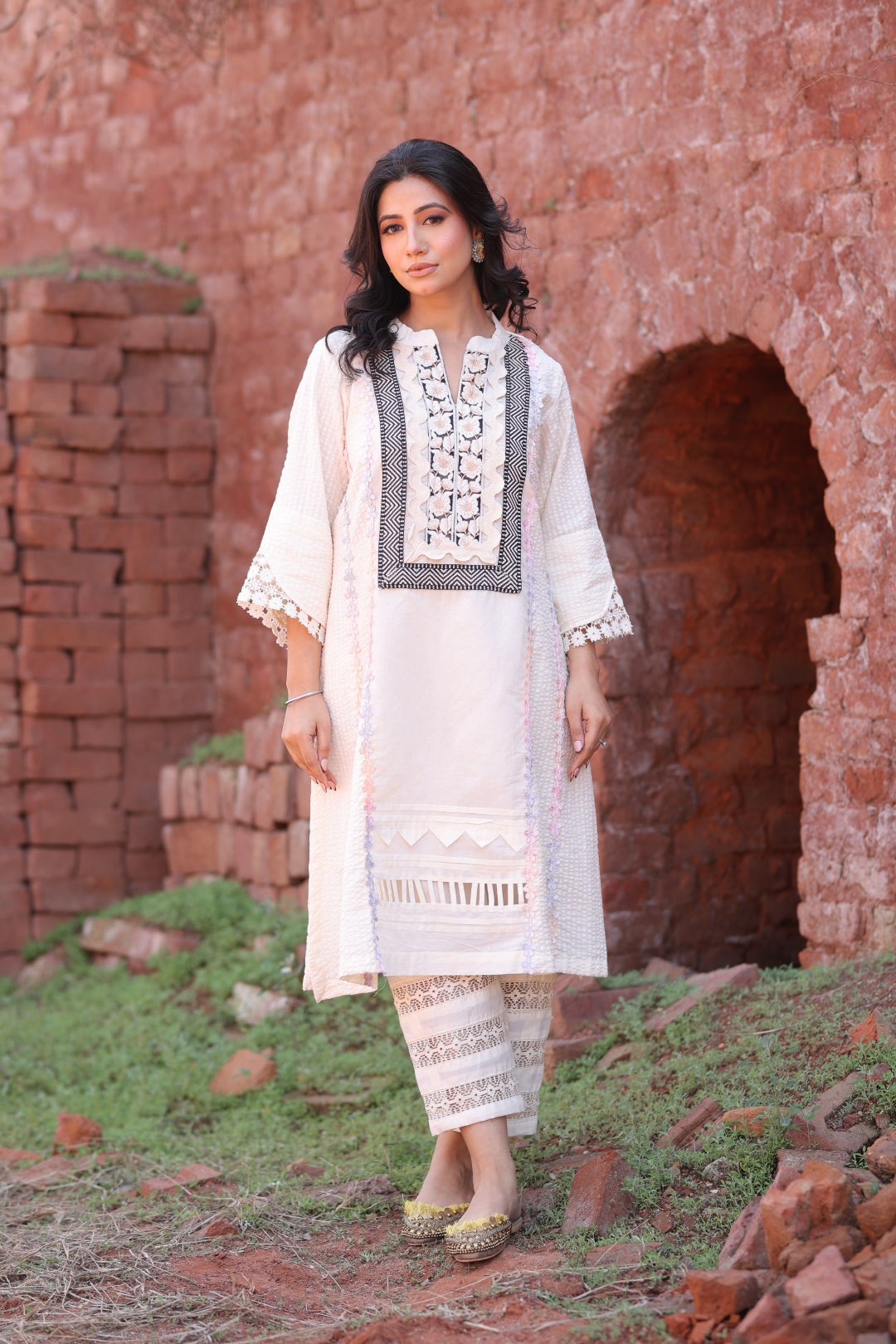 Model in ivory embroidered kurta with lace pants in rustic backdrop