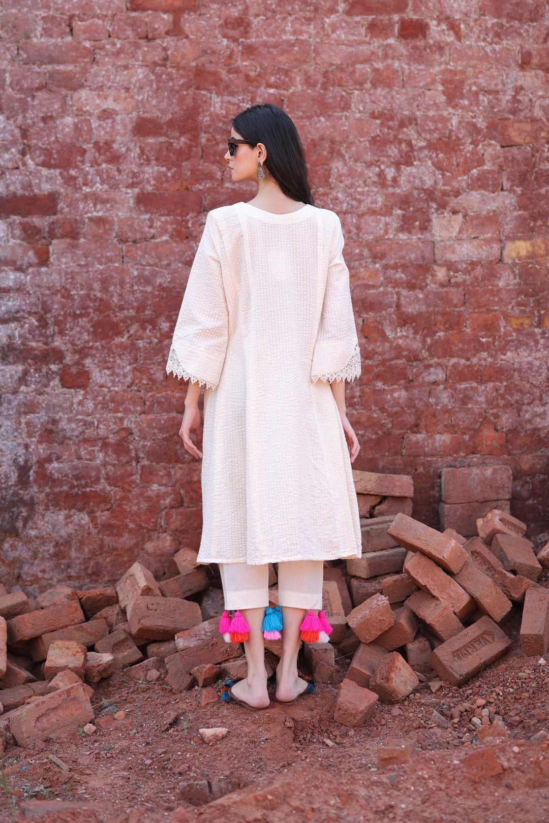 Back profile of the ivory kurta, showcasing fabric flow and tassel fall