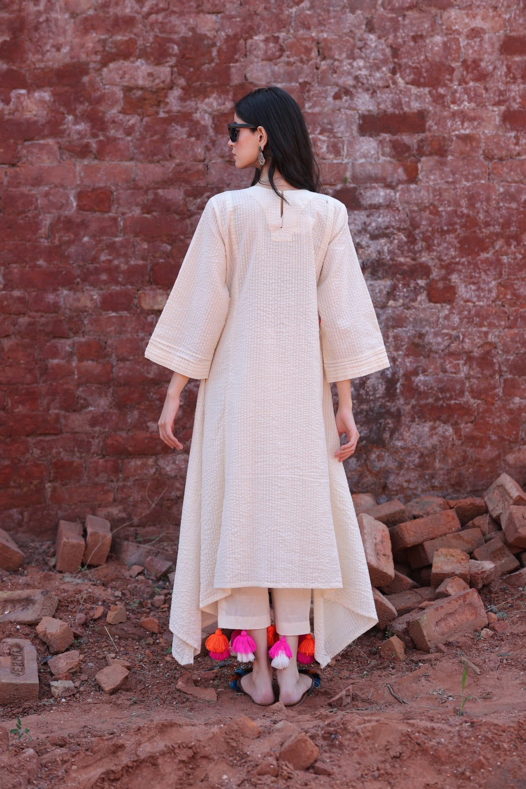 Flowing back silhouette of high-low ivory kurta with tassel hem detail.