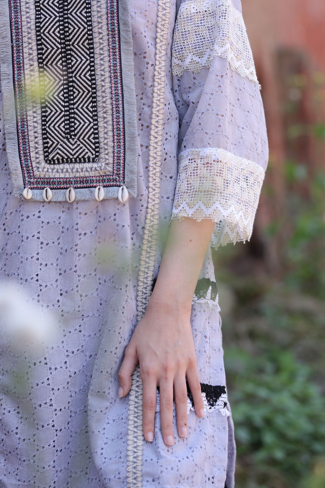 Close-up of monochrome embroidery and shell detail on placket