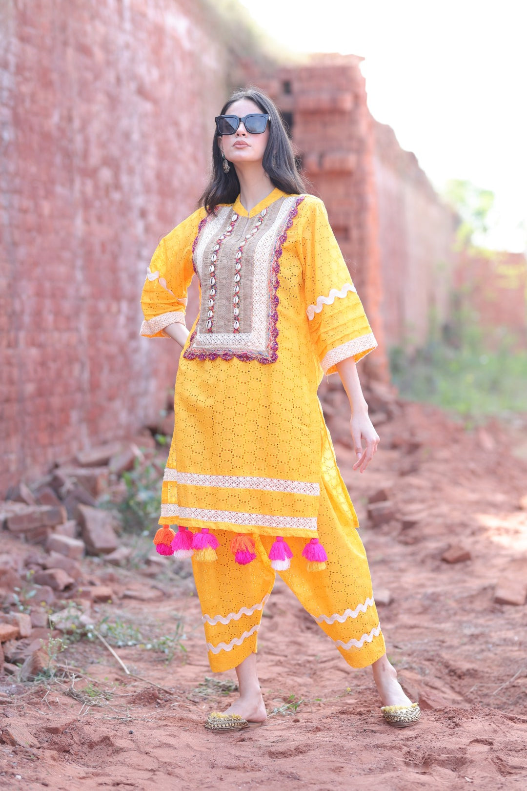 Model in mustard chikankari kurta set with shell-embellished placket and tassels