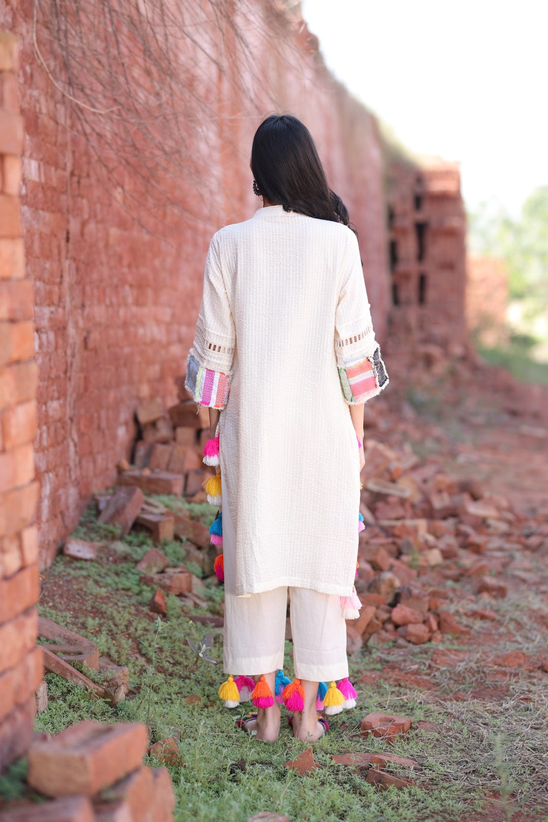Back of ivory kurta with hand-tied tassels along hem and sleeves