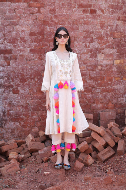 Model wearing ivory kurta set with gold embroidery and multicolour tassels, front-facing