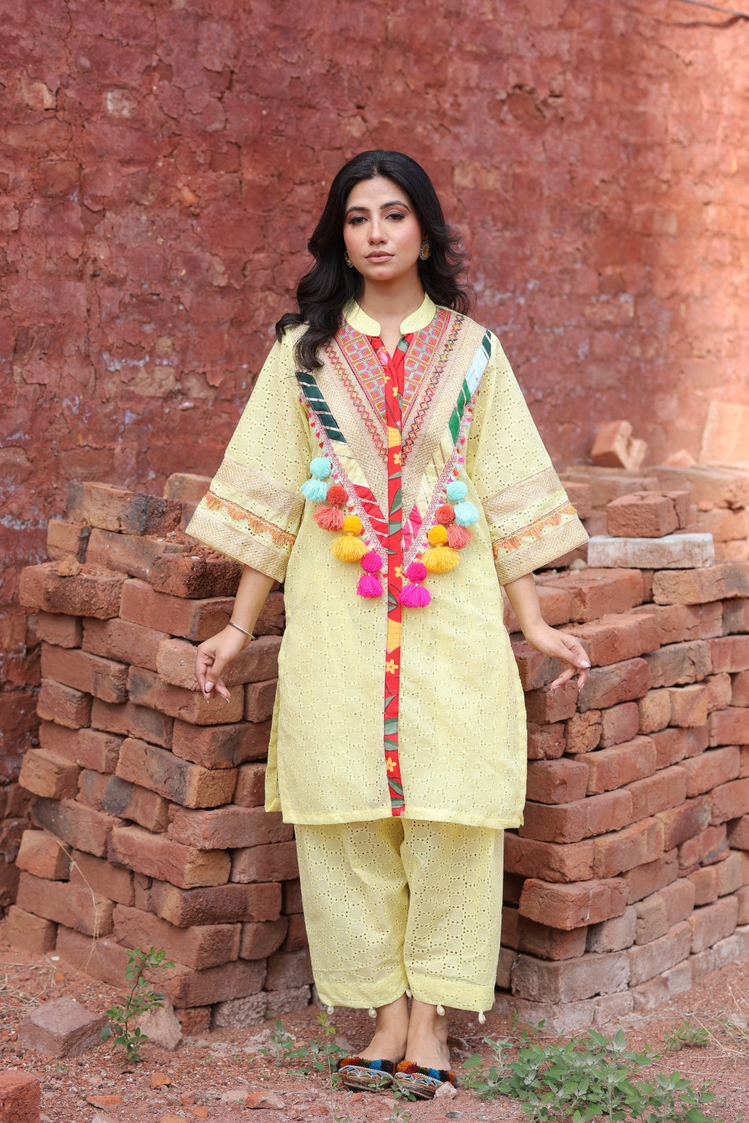 Model wearing yellow chikankari kurta with tribal mirror yoke and tassels – front view
