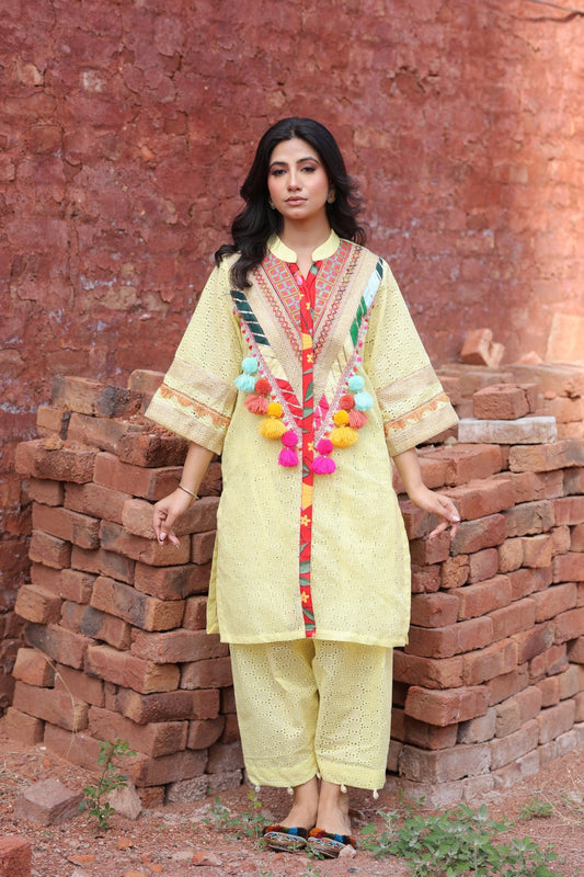 Model wearing yellow chikankari kurta with tribal mirror yoke and tassels – front view