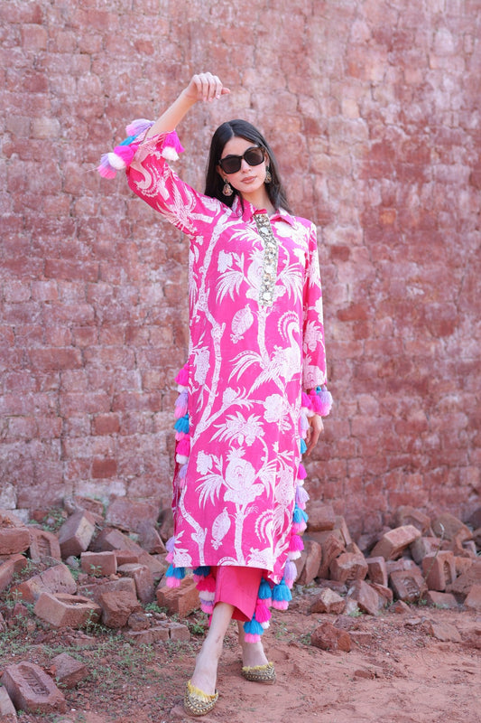 Model in vibrant pink tropical kurta set with multicolour tassels, standing confidently